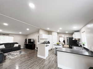 Kitchen with white cabinetry, appliances with stainless steel finishes, hardwood / wood-style floors, sink, and kitchen peninsula