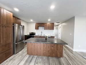 Kitchen featuring appliances with stainless steel finishes, sink, light hardwood / wood-style floors, and a center island