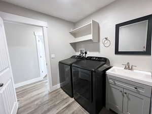 Laundry room featuring cabinets, light wood-type flooring, sink, and washer and dryer