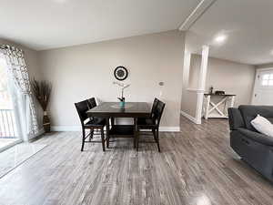 Dining room featuring hardwood / wood-style flooring, ornate columns, and lofted ceiling