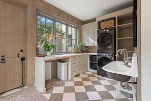 Laundry area with cabinets, wood walls, and stacked washer / dryer