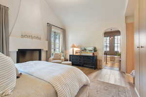 Bedroom with high vaulted ceiling, multiple windows, and light hardwood / wood-style flooring