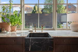 Kitchen with sink, light stone counters, and dark brown cabinets