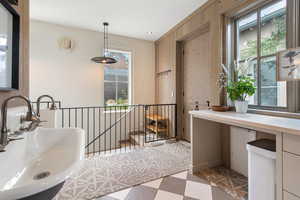 Bathroom featuring a tub to relax in, wood walls, and sink