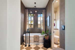 Bathroom with toilet, a chandelier, and a bathtub