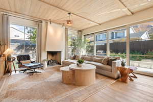 Sunroom / solarium featuring wooden ceiling and a fireplace