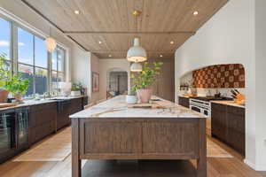 Kitchen featuring light hardwood / wood-style floors, dark brown cabinets, a wealth of natural light, and pendant lighting