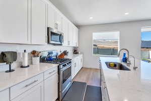 Kitchen with white cabinets, stainless steel appliances, and light stone counters