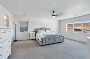 Bedroom with a textured ceiling, light colored carpet, and ceiling fan