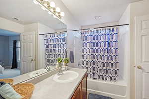 Bathroom featuring shower / bath combo with shower curtain, vanity, and a textured ceiling