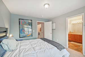 Bedroom with ensuite bathroom, washer / dryer, sink, and carpet floors