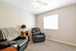 Sitting room featuring light colored carpet and ceiling fan