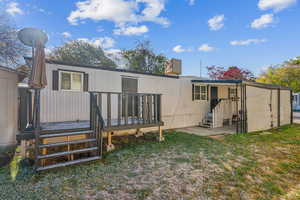 Rear view of house featuring new wooden deck and a patio area