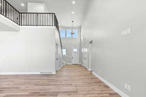 Entryway with a towering ceiling, light hardwood / wood-style floors, and an inviting chandelier