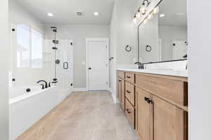 Bathroom featuring tile patterned flooring, shower with separate bathtub, and vanity