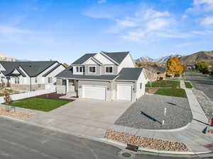 View of front of property featuring a mountain view, a front lawn, and a garage