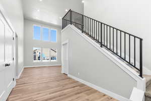 Stairs featuring a towering ceiling and hardwood / wood-style flooring