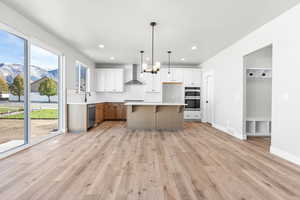 Kitchen with a center island, white cabinets, hanging light fixtures, and appliances with stainless steel finishes