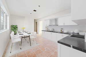 Kitchen featuring white cabinets, light tile patterned flooring, wall chimney range hood, and stainless steel gas stovetop