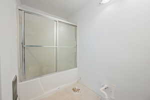 Bathroom with tile patterned floors and shower / bath combination with glass door