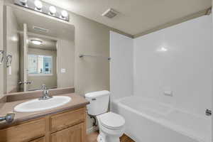 Full bathroom featuring vanity, a textured ceiling,  shower combination, hardwood / wood-style floors, and toilet