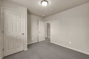 Unfurnished bedroom featuring a textured ceiling and light carpet