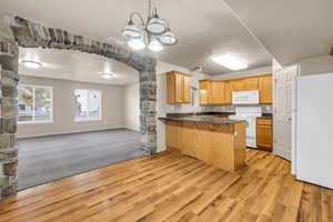 Kitchen with kitchen peninsula, white appliances, sink, and light wood-type flooring