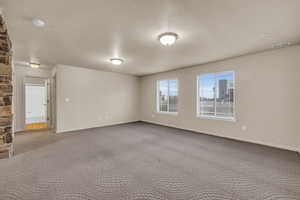 Carpeted spare room featuring a textured ceiling