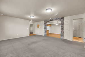 Unfurnished living room featuring carpet and a textured ceiling