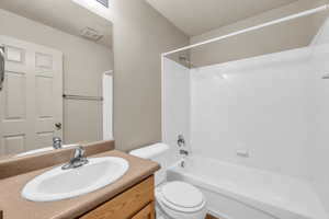 Full bathroom with vanity, a textured ceiling, toilet, and bathtub / shower combination