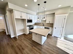 Kitchen featuring appliances with stainless steel finishes, decorative light fixtures, sink, white cabinets, and a center island