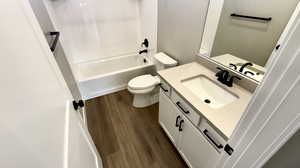 Full bathroom featuring hardwood / wood-style flooring, vanity, toilet, and shower / bath combination