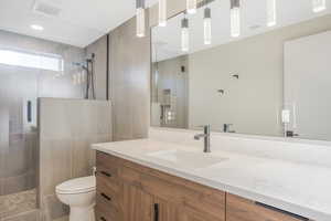 Bathroom featuring tile walls, vanity, toilet, and a shower with door