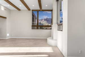 Tiled spare room featuring beamed ceiling