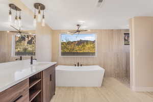 Bathroom with vanity, wood-type flooring, ceiling fan with notable chandelier, and a tub