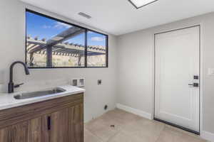 Laundry area featuring hookup for a washing machine, sink, light tile patterned floors, and hookup for an electric dryer