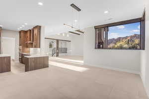 Kitchen featuring kitchen peninsula, tasteful backsplash, wall chimney range hood, double oven, and decorative light fixtures