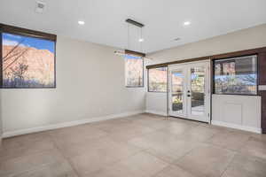 Empty room featuring a mountain view, french doors, and light tile patterned floors