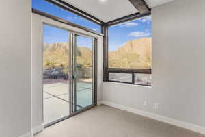 Doorway with a mountain view, light carpet, and beam ceiling