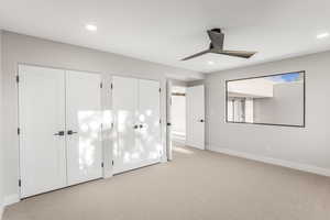 Unfurnished bedroom featuring multiple closets, light colored carpet, and ceiling fan