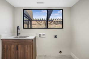 Clothes washing area featuring light tile patterned floors, washer hookup, sink, and electric dryer hookup