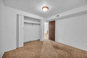 Unfurnished bedroom with carpet flooring, a textured ceiling, and a closet