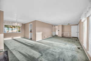 Spare room with carpet, an inviting chandelier, and ornamental molding