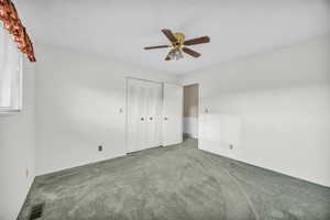 Unfurnished bedroom with ceiling fan, carpet flooring, and a closet