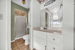 Bathroom with vanity, tile patterned floors, toilet, and a shower with door