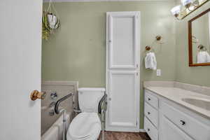 Bathroom featuring vanity, toilet, and a washtub