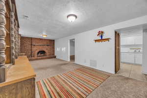 Unfurnished living room with a fireplace, light carpet, and a textured ceiling