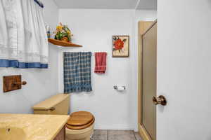 Bathroom featuring tile patterned flooring, vanity, toilet, and a shower with shower door