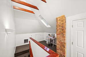 Stairs with lofted ceiling with skylight and carpet