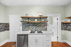 Kitchen featuring white cabinets, hardwood / wood-style floors, sink, tasteful backsplash, and stainless steel dishwasher